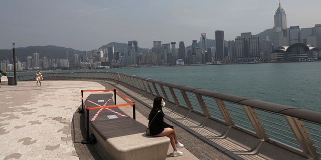 A woman sits next to a cross made with tape on a chair for practicing social distancing to help curb the spread of the coronavirus COVID-19, in Hong Kong, Wednesday, April 15, 2020.