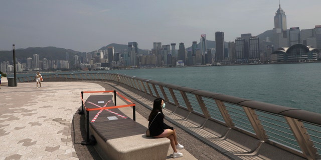 A woman sits next to a cross made with tape on a chair for practicing social distancing to help curb the spread of the coronavirus COVID-19, in Hong Kong, Wednesday, April 15, 2020.