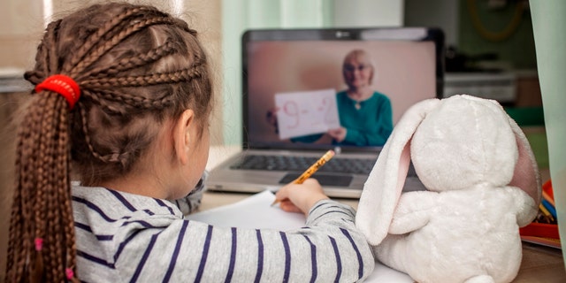 Pretty stylish schoolgirl studying math during her online lesson at home, social distance during quarantine, self-isolation, online education concept