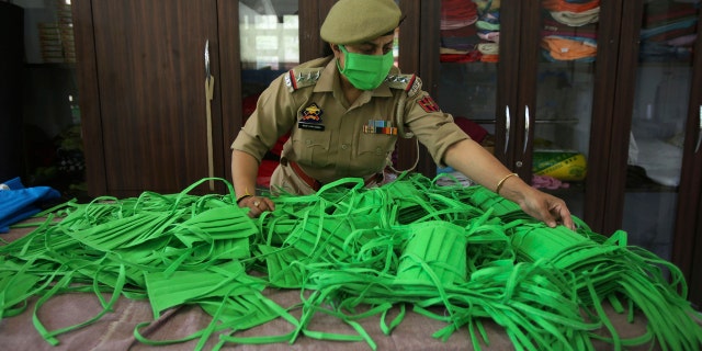 An officer checks the quality as Jammu and Kashmir police personnel make face masks and personal protective gear amid COVID-19 outbreak in Jammu, India, Wednesday.