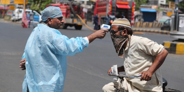 An Indian health worker checks the temperature of a man during lockdown to prevent the spread of new coronavirus in Ahmedabad, India, Wednesday.