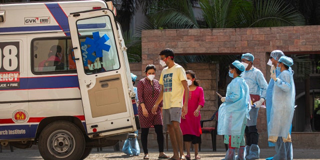 People from an apartment complex board an ambulance to be taken to a hospital for quarantine after a person was found to be COVID-19 positive, in Gauhati, India.