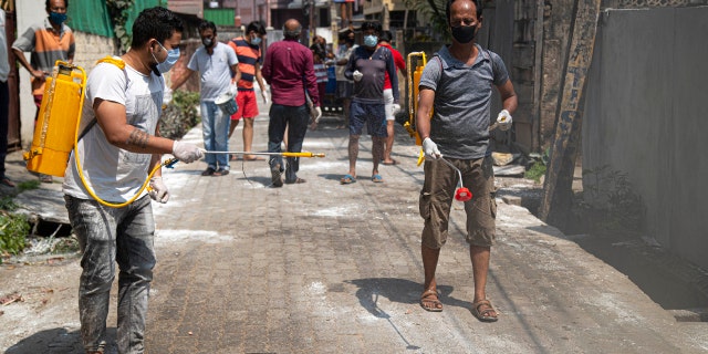 Residents sanitize their area as a preventive measure against the COVID-19 in Gauhati, India, Sunday, April 5, 2020.