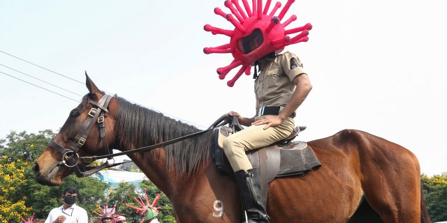 An Indian policeman wearing a virus themed helmet rides on a horse during an awareness rally aimed at preventing the spread of new coronavirus in Hyderabad, India, Thursday.