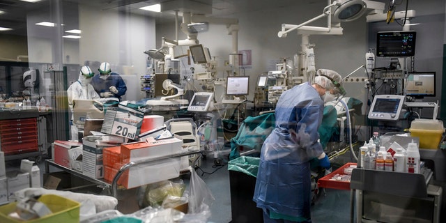 In this photograph taken from behind a window, doctors inside a Covid-19 intensive care unit of San Matteo Hospital, in Pavia, northern Italy, Thursday, March 26, 2020. The San Matteo hospital is where Patient 1, a 38-year-old Unilever worker named Mattia, was kept since he tested positive for Covid-19 on Feb. 21 and opened ItalyÕs health care crisis. The new coronavirus causes mild or moderate symptoms for most people, but for some, especially older adults and people with existing health problems, it can cause more severe illness or death. (Claudio Furlan/LaPresse via AP)
