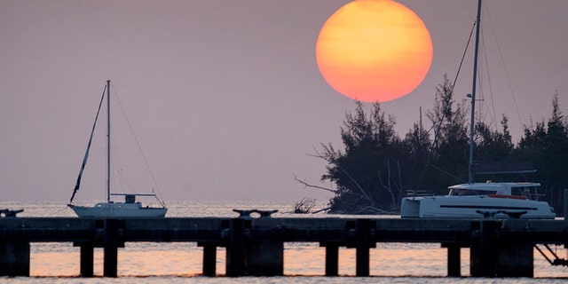 The sun sets Friday, April 17, 2020, over a quiet Key West Harbor in Key West, Fla. Gov. Ron Desantis opened Florida beaches Friday as a first move to reopen the state after the coronavirus outbreak. (Rob O'Neal/The Key West Citizen via AP)