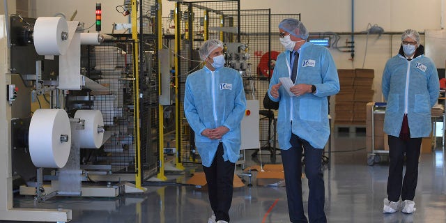 Macron, left, wearing protective suit and a face mask, visits the Kolmi-Hopen protective face masks factory in Saint-Barthelemy-d'Anjou near Angers, central France, on Tuesday. (Loic Venance, Pool via AP)