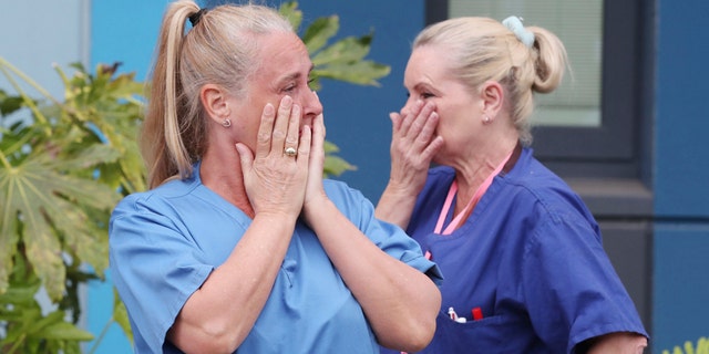 Staff stand outside Salford Royal Hospital in Manchester, England, on April 28, 2020, during a minute's silence to pay tribute to the NHS staff and key workers who died during the coronavirus outbreak.