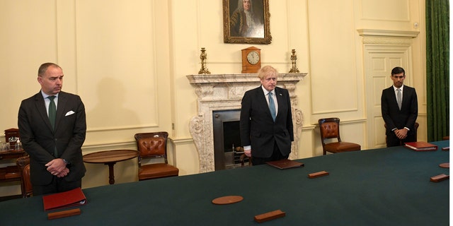 Britain's Prime Minister Boris Johnson, center, Chancellor of the Exchequer Rishi Sunak, right, and Cabinet Secretary Mark Sedwill stand inside 10 Downing Street, London, Tuesday April 28, 2020, during a minute's silence to pay tribute to the NHS staff and key workers who have died during the coronavirus outbreak. (Stefan Rousseau/PA via AP)