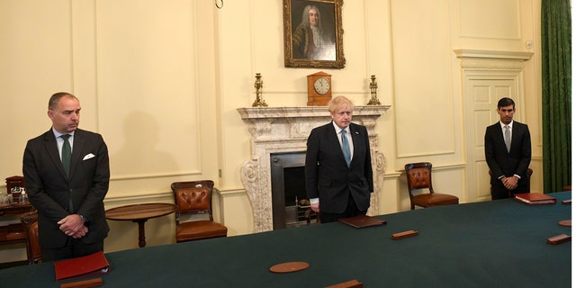 Britain's Prime Minister Boris Johnson, center, Chancellor of the Exchequer Rishi Sunak, right, and Cabinet Secretary Mark Sedwill stand inside 10 Downing Street, London, Tuesday April 28, 2020, during a minute's silence to pay tribute to the NHS staff and key workers who have died during the coronavirus outbreak. (Stefan Rousseau/PA via AP)
