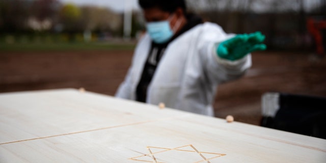 Gravedigger Thomas Cortez directs his coworker where to stop the pickup truck carrying a casket as it's brought to a plot for burial at Hebrew Free Burial Association's Mount Richmond Cemetery in the Staten Island borough of New York, April 8. (AP Photo/David Goldman)