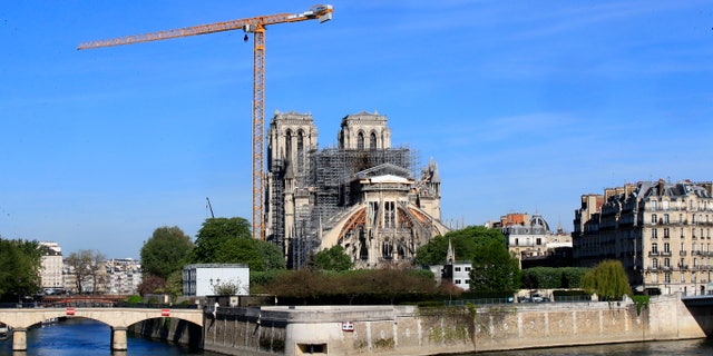 A crane stands by Notre Dame Cathedral on April 15. Work began Monday to refit the construction site to protect workers from the virus and allow cleanup efforts to resume. (AP)
