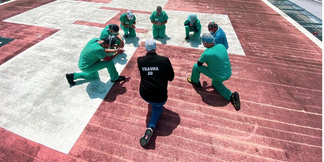 Hospital staff at Jackson South Medical Center pray on the hospital's helipad.