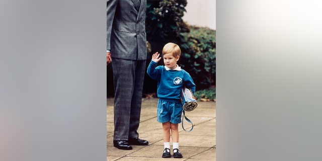 In this Sept. 16, 1987 file photo, Britain's Prince Harry waves to photographers whilst holding a 'Thomas The Tank Engine' bag on his first day at a kindergarten in Notting Hill, West London.