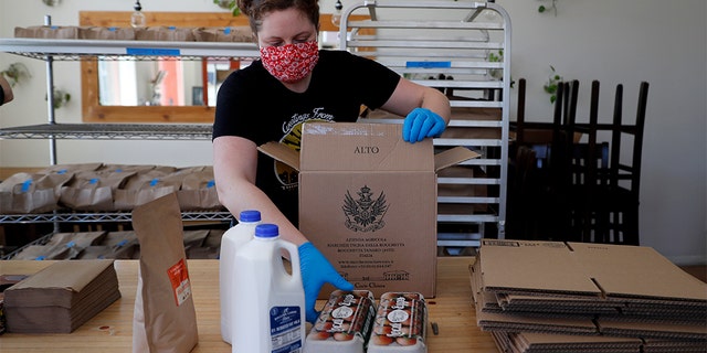 Monica Mileur packs grocery items into a box at Union Loafers restaurant Friday, April 10, 2020, in St. Louis. (AP Photo/Jeff Roberson)