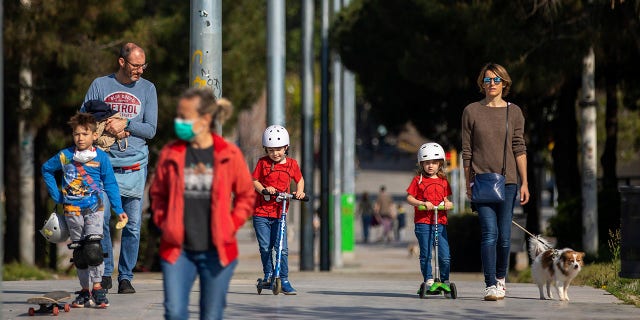 Families walk in the sunshine along a boulevard in Barcelona on Sunday, ending six weeks of complete seclusion, as the lockdown to combat the spread of coronavirus continues. (AP Photo/Emilio Morenatti)