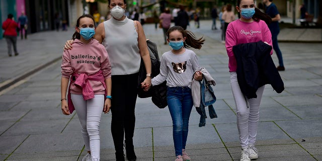 A family wearing face masks to protect of the coronavirus go for a walk at Carlos III promenade, in Pamplona, northern Spain, on Sunday. (AP Photo/Alvaro Barrientos)