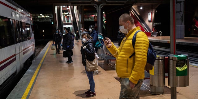 Commuters wearing face masks to protect against coronavirus at the platform of Atocha train station in Madrid, Spain, Monday, April 13, 2020. Confronting both a public health emergency and long-term economic injury, Spain is cautiously re-starting some business activity to emerge from the nationwide near-total freeze that helped slow the country's grim coronavirus outbreak. (AP Photo/Bernat Armangue)