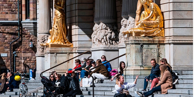 People sitting and enjoying the spring weather outside the Royal Dramatic Theatre in Stockholm last Wednesday. (Jonathan NACKSTRAND / AFP via Getty Images)