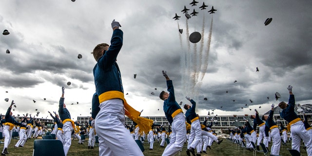 United States Air Force Academy cadets celebrate their graduation as a team of F-16 Air Force Thunderbirds fly over the academy on April 18, 2020 in Colorado Springs, Colorado. 