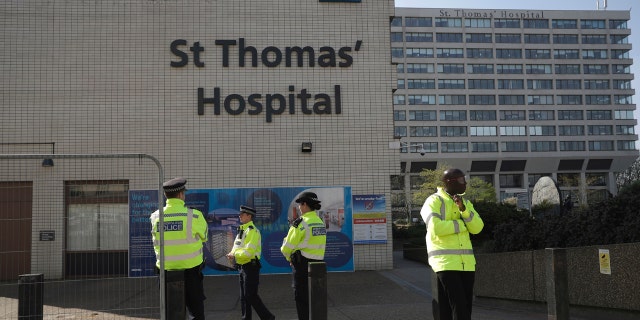 Three police officers at left and a security guard at right guard an entrance outside St Thomas' Hospital in London, where British Prime Minister Boris Johnson was being treated for coronavirus.