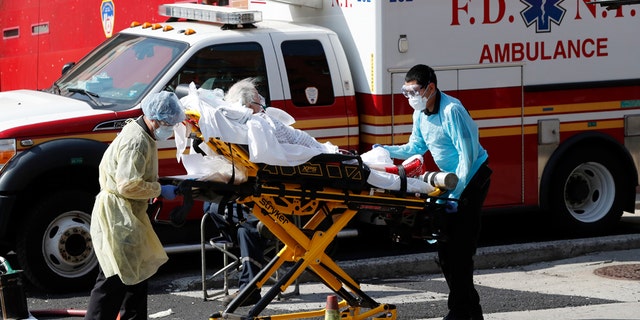 A patient is transferred from Elmhurst Hospital Center to a waiting ambulance during the current coronavirus outbreak, Tuesday, April 7, 2020, in New York. New York Gov. Andrew Cuomo said last week that the city's overtaxed hospitals could move patients to other medical facilities to ease the burden on local hospitals. (AP Photo/Kathy Willens)