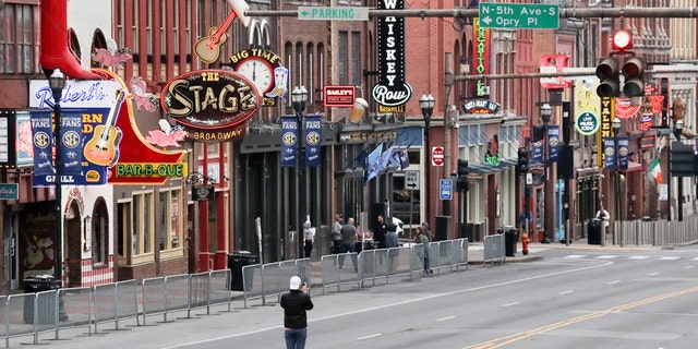 A man stands in the middle of Broadway to take a photo where the streets and sidewalks are normally filled in Nashville, Tenn. on March 23. (AP Photo/Mark Humphrey, File)