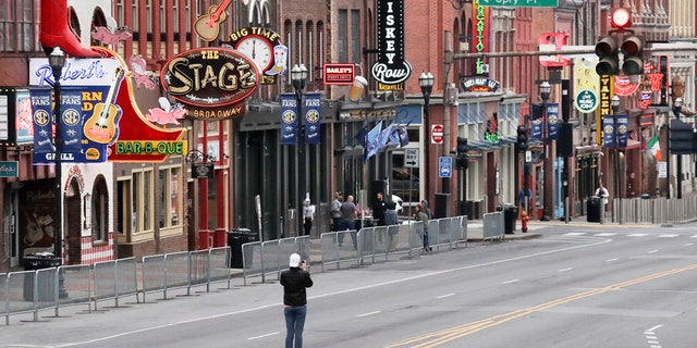 A man stands in the middle of Broadway to take a photo where the streets and sidewalks are normally filled in Nashville, Tenn. on March 23. (AP Photo/Mark Humphrey, File)