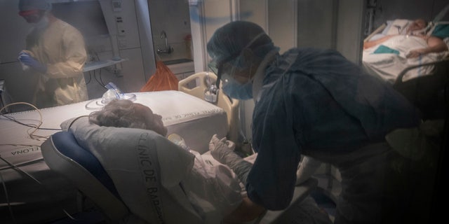 Health care workers assist a COVID-19 patient at one of the intensive care units (ICU) of the Clinic hospital in Barcelona, Spain, on Wednesday. (AP Photo/Ricardo Garcia Vilanova)