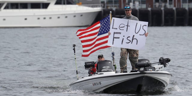 A protester holds a sign that reads "Let Us Fish" on a boat on Lake Union near Gas Works Park in Seattle on Sunday during a protest against Washington state's current ban on fishing. A day later, Inslee permitted fishing among other outdoor activities. (AP Photo/Ted S. Warren)