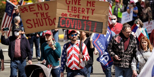 Demonstrators begin to gather at a protest opposing Washington state's stay-home order to slow the coronavirus outbreak Sunday, April 19, 2020, in Olympia, Wash.  (AP Photo/Elaine Thompson)