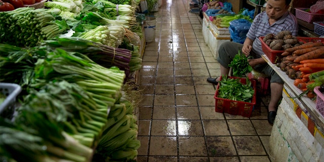 A vendor prepares vegetables for sale at a wet market in Shenzhen, China. (AP Photo/Ng Han Guan)