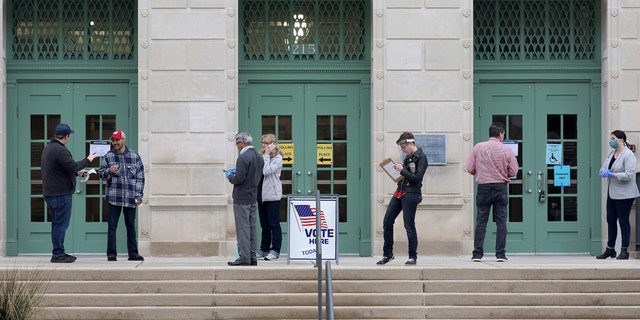 Election workers and voters keep a distance from each other during the state's presidential primary election Tuesday, April 7, 2020 outside the Madison Municipal Building in Madison, Wis. Voters across the state are ignoring a stay-at-home order in the midst of a pandemic to participate in the state's presidential primary election. (John Hart/Wisconsin State Journal via AP)