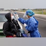 A nurse from the Ministry of Public Health takes a sample from a person on a motorcycle, at a coronavirus mobile test site in Asuncion, Paraguay, April 8, 2020.