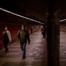 Passengers wearing face masks to prevent the spread of coronavirus, walk along a tunnel connecting platforms in a metro station in Barcelona, Spain, April 15, 2020. 
