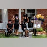 The family of Larry Hammond wave as a line of cars with friends and family, who could not attend his funeral because of limits of gatherings of more than 10 people, due to the coronavirus pandemic, pass by their home, in New Orleans, April 22, 2020.