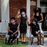 The family of Larry Hammond wave as a line of cars with friends and family, who could not attend his funeral because of limits of gatherings of more than 10 people, due to the coronavirus pandemic, pass by their home, in New Orleans, April 22, 2020.