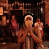A woman wearing a mask as a precaution amid the spread of the coronavirus prays under street lamp light outside the closed Saint George Church in Rio de Janeiro, Brazil, April 23, 2020.