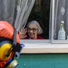 A woman waves to a city worker dressed in a hazmat suit as he disinfects the streets in her neighborhood as a precaution against the spread of the new coronavirus, in Santiago, Chile, Wednesday, April 15, 2020. (AP Photo/Esteban Felix)