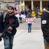 Protesters carry rifles near the steps of the Michigan State Capitol building in Lansing.