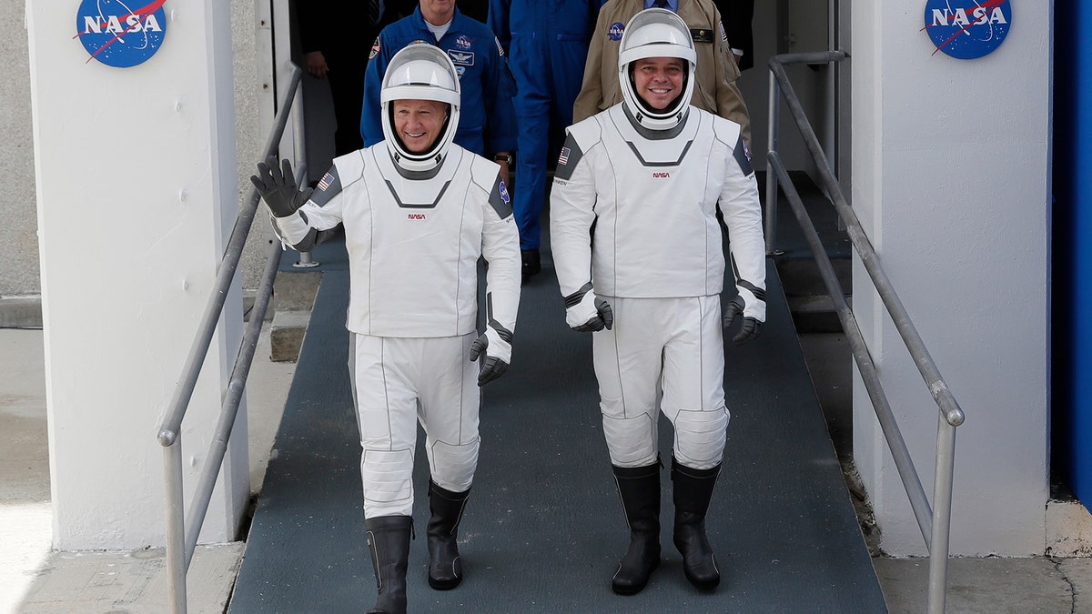 NASA astronauts Douglas Hurley, left, and Robert Behnken wave as they walk out of the Neil A. Armstrong Operations and Checkout Building on their way to Pad 39-A, at the Kennedy Space Center in Cape Canaveral, Fla., Wednesday, May 27, 2020. (AP Photo/John Raoux)