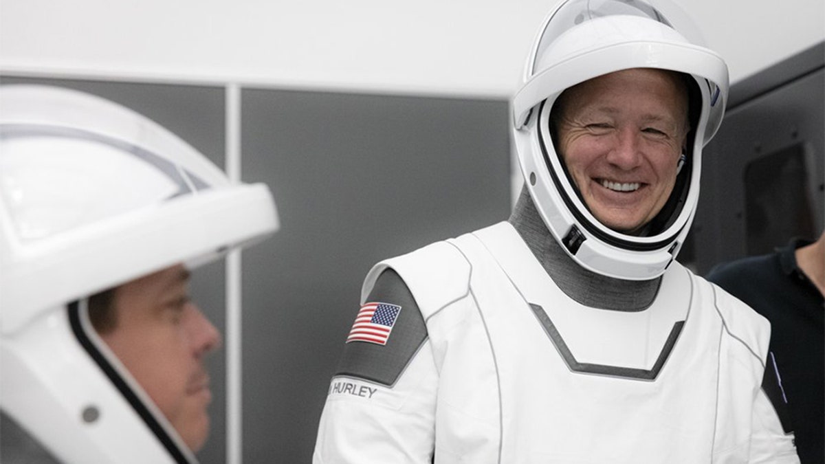 This Thursday, March 19, 2020 photo made available by SpaceX shows NASA astronauts Bob Behnken and Doug Hurley during flight simulator testing at the Kennedy Space Center in Cape Canaveral, Fla., with SpaceX teams in Firing Room 4 at NASA's Kennedy Space Center, SpaceX's Mission Control in Hawthorne, Calif., and NASA flight controllers in Mission Control Houston, for a full simulation of launch and docking of the Crew Dragon spacecraft.