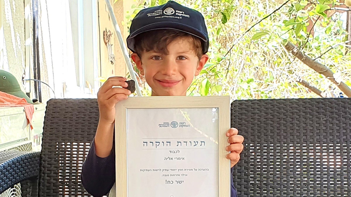 Imri Elya with the ancient tablet and the certificate of recognition given to him by the Israel Antiquities Authority.