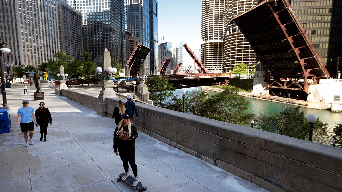 Pedestrian make their way along the Chicago River early Sunday morning, May 31, 2020, as several street bridges remain closed after a night of unrest and protests over the death of George Floyd, a black man who was in police custody in Minneapolis. Floyd died after being restrained by Minneapolis police officers on Memorial Day. (AP Photo/Charles Rex Arbogast)