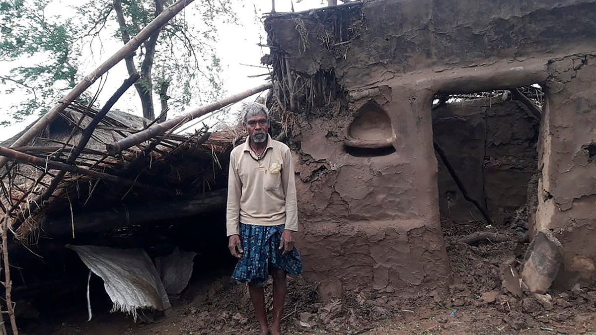 This photo provided by the Indian Red Cross Society shows a villager standing outside his damaged house after Cyclone Amphan, the equivalent of a category 3 hurricane, hit the area in Bhadrak district of Orissa state, May 21. (Indian Red Cross Society via AP)