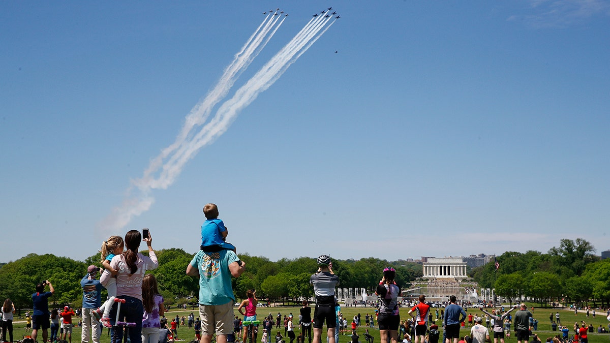People view the U.S. Navy Blue Angels and U.S. Air Force Thunderbirds as they fly over the National Mall in Washington, Saturday, May 2, 2020. The flyover was in salute to first responders in the fight against the coronavirus pandemic. (AP Photo/Patrick Semansky)