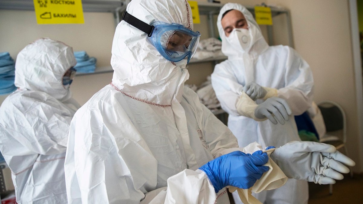 Medical workers put on protective gear in order to assist coronavirus patients at the intensive care unit of Vinogradov City Clinical Hospital in Moscow. Three Russian health care workers have fallen out of hospital windows in recent weeks after complaints about a lack of equipment and becoming infected. (AP Photo/Pavel Golovkin)