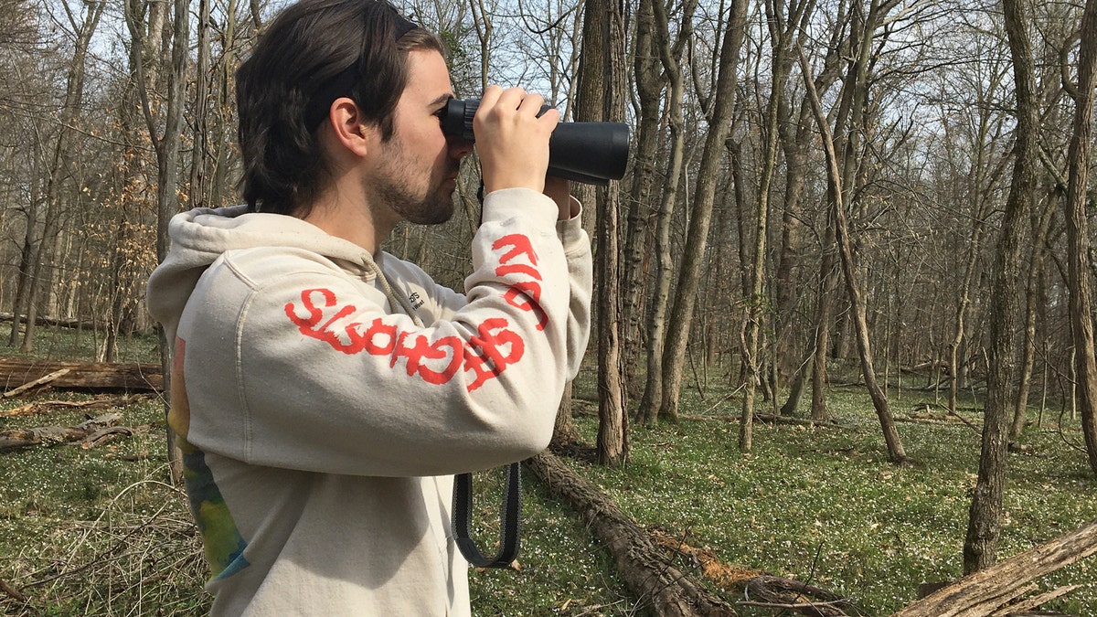 Conner Brown uses binoculars to look for birds in Cedar Island, Maryland.