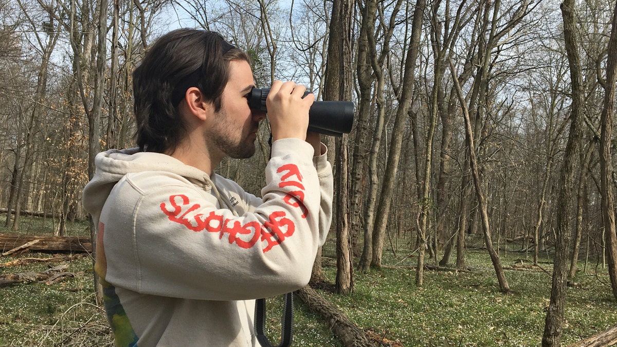 Conner Brown uses binoculars to look for birds in Cedar Island, Maryland.