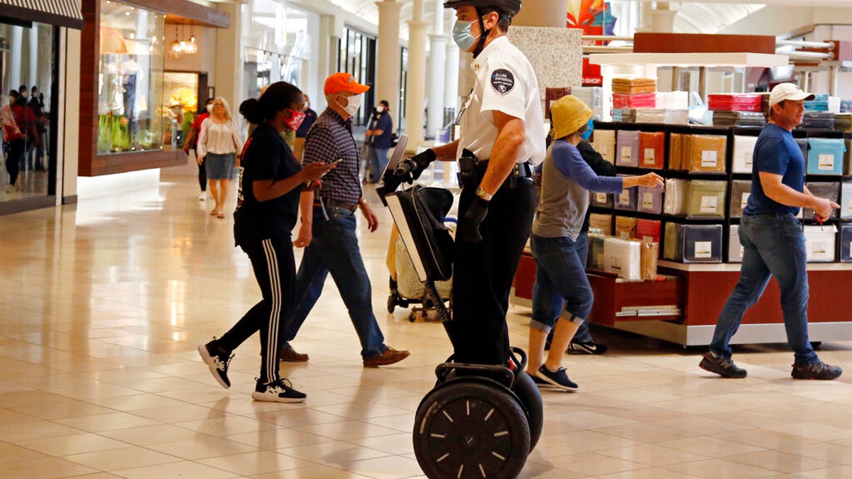 A security guard wearing a mask and riding a Segway patrols inside Penn Square Mall as the mall reopens Friday, May 1, 2020, in Oklahoma City.